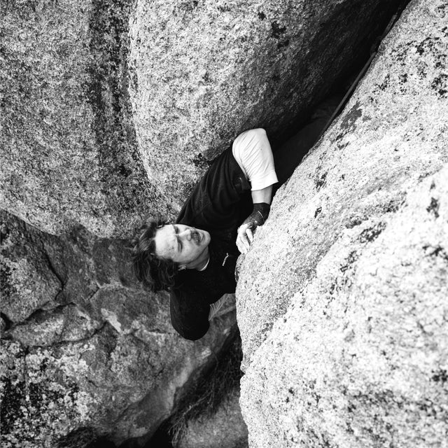 Joel climbing while wearing the black logo tee with white undershirt